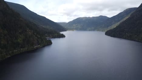 A-tilting-drone-video-revealing-a-lake-between-two-mountains-on-a-sunny-day