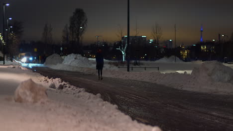 Young-woman-walks-on-icy-city-street-on-dark-winter-pre-dawn-morning