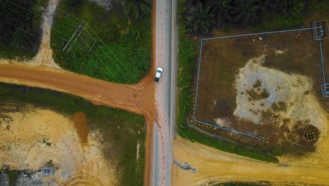 Cinematic-Drone-Footage-of-white-Mazda-Light-Vehicle-sequences-in-the-middle-of-the-jungle-surrounded-by-palm-oil-trees-deforestation-located-in-Indonesia-in-full-HD