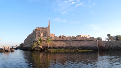 Ancient-temple-of-Philae-from-a-boat-during-sunrise-in-Aswan,-Egypt