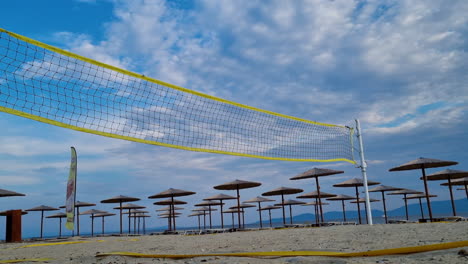 Beach-Volleyball-net-near-the-sunbeds-and-straw-beach-umbrellas