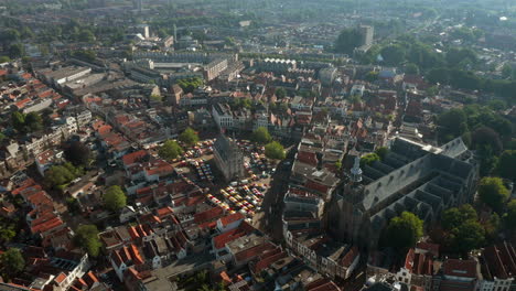 Flying-Towards-The-Prominent-Landmark-And-Structure-Of-Sint-Jan-Church,-Old-Town-Hall-And-Market-Stands-In-In-Gouda-Metropolitan,-Netherlands