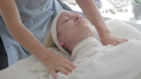 Masseuse-Covering-Woman's-Face-with-Hot-Towel-for-Facial-Massage