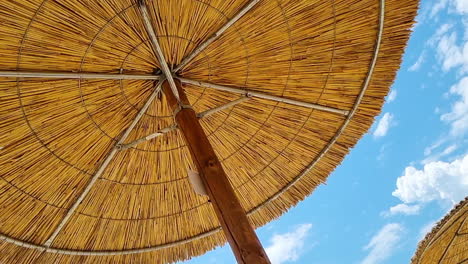 Under-the-reed-straw-beach-umbrella-and-clear-blue-sky-on-a-sunny-day