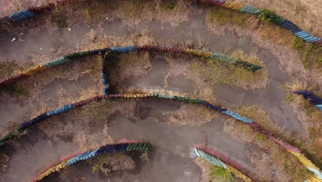Aerial-top-down-shot-of-empty-circular-overgrown-labyrinth-in-scenic-landscape-during-daytime
