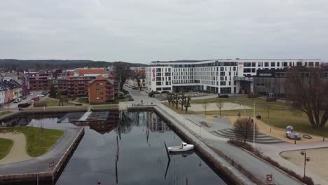Aerial-approaching-Scandic-hotel-Kristiansand---Moving-forward-close-to-water-surface-while-ascending-and-passing-playground-towards-hotel-building
