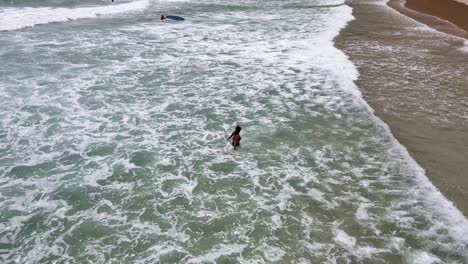 Aerial-View-Of-Female-Tourist-Standing-In-Nai-Harn-Beach-As-Waves-Break-Past-Her