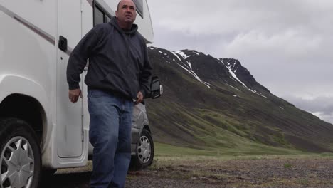 Man-getting-out-of-RV-and-looking-around-at-Mountain