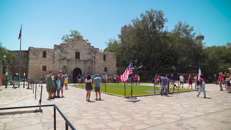 Das-Alamo-Gebäude-Mit-Einer-Großen-Touristengruppe-Und-Fahnen-Davor