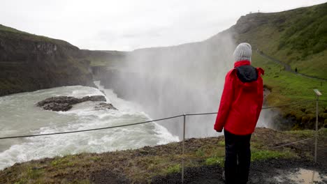 Gulfoss-waterfalls-in-Iceland-with-gimbal-video-walking-behind-woman-looking-at-falls-in-slow-motion