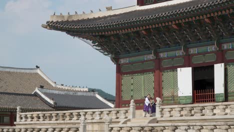 Man-and-woman-in-korean-traditional-clothes-hanbok-bowing-or-greeting-one-another-near-Geunjeongjeon-throne-hall-in-Gyeongbokgung-Palace,-Seoul-South-Korea