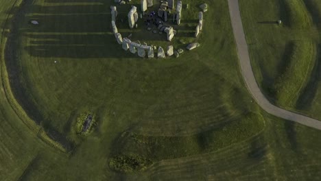Stonehenge-top-down-across-the-stone-circle,-green-fields-and-sun-shadows