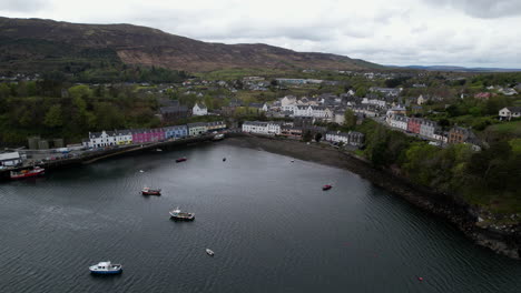Aerial-view-orbiting-above-peaceful-Scottish-Portree-harbour-maritime-coast-picturesque-colourful-coastal-houses