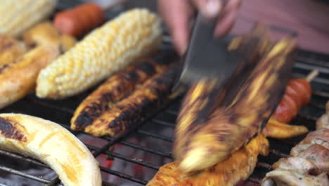 Close-Up-View-Of-Vendor-Slicing-Charcoaled-Banana-On-Grill-Beside-Corn-Cob-For-Customer-In-San-Cristobel-In-The-Galapagos