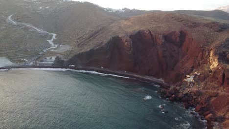 Mirando-Hacia-La-Playa-Roja-En-Santorini-Desde-El-Mar-Al-Atardecer