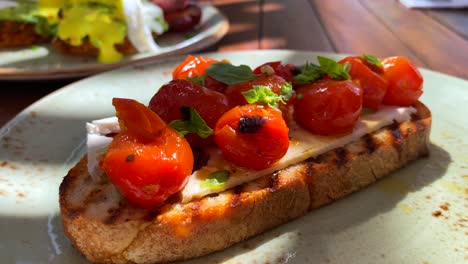 Delicious-bruschetta-sourdough-toast-with-cherry-tomatoes-and-fresh-basil,-traditional-italian-breakfast-brunch-dish-at-a-restaurant,-4K-shot