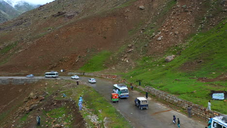 Drone-shot-of-vehicles-on-the-Babusar-Pass-mountain-pass-in-Pakistan-in-the-Kaghan-Valley-and-children-running-on-the-road