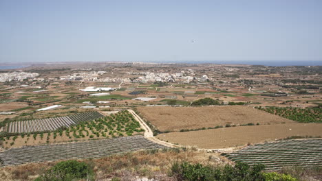 Paisaje-Rural-De-4k-Con-El-Mar-Mediterráneo-Y-Un-Pequeño-Pueblo-A-Lo-Lejos-En-La-Isla-De-Malta-Durante-Un-Caluroso-Día-De-Verano