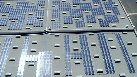 Photovoltaic-solar-panels-on-commercial-building-roof,-renewable-energy-concept,-Aerial-topdown-sideways