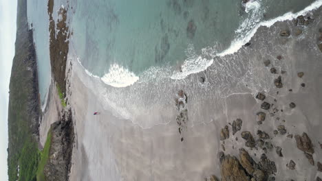 Un-Video-Vertical-De-Kennack-Sands-En-Cornualles,-Inglaterra,-Que-Muestra-La-Playa-Y-El-Promontorio-Rocoso