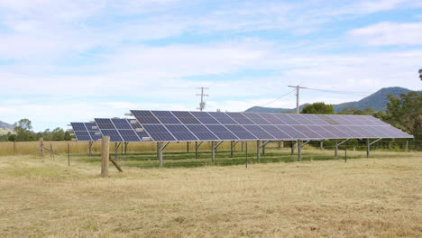 Rows-Of-Solar-Panels-In-Rural-Australian-Paddock-With-Blue-Sky,-4K-Drone