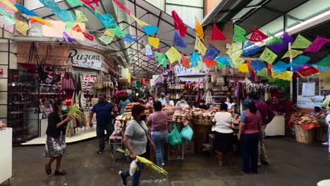 Puestos-Del-Mercado-Local-En-El-Pequeño-Centro-Comercial-Benito-Juarez-Market-Mexico,-Personas-Consumidores-Reunidas-Caminando-Comprando-Bienes,-Mercadería-Exhibida-En-Los-Estantes-De-Las-Tiendas