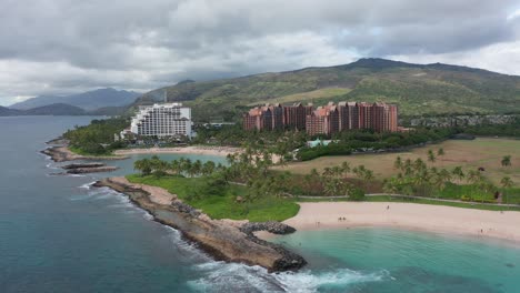 Aerial-dolly-shot-along-coastal-lagoons-with-luxury-resorts-in-the-background-on-the-island-of-O'ahu,-Hawaii