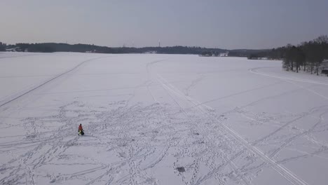Wide-panning-aerial-footage-revealing-the-vastness-of-a-frozen-lake-with-a-single-male-walking-across-showing-the-scale-of-the-lake