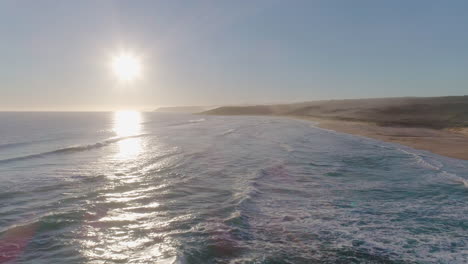 Aerial-shot-at-sunset-over-a-beach-as-waves-crash-into-shore-in-South-Australia