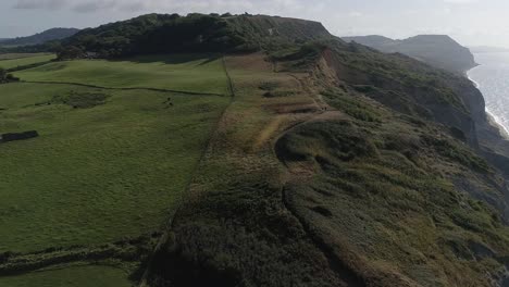 Golden-cap-and-Charmouth-beach-cliffs-are-revealed-with-an-aerial-track-from-inland-to-out-to-sea-looking-east