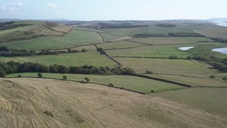 Wide-aerial-looking-east-over-the-fields-behind-the-fleet-lagoon-near-Chesil-Beach-and-Abbotsbury,-Dorset