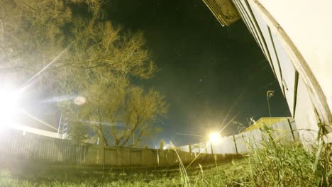 NIGHT-LAPSE---Moon-going-down-and-stars-flying-by-over-a-tree-in-a-yard-next-to-a-home