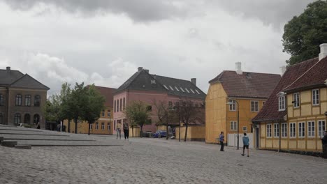 Slow-motion-shot-of-people-walking-on-cobblestones-in-front-of-old-colourful-houses-in-Roskilde,-Denmark