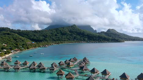 Aerial-panning-shot-of-the-Bora-Bora-Mountains-and-the-Overwaterbungalows-in-the-pacific-ocean,-Bora-Bora,-French-Polynesia