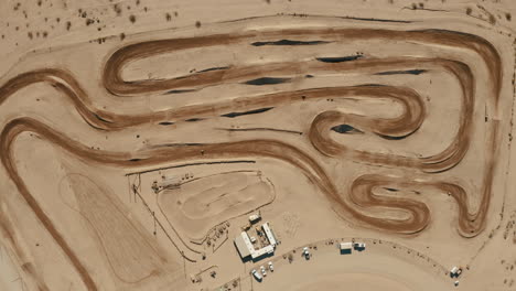 Motocross-dirt-circuit-during-race,-High-aerial-view-from-above-zooming-in