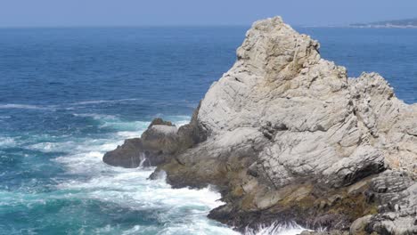 Ultra-slow-motion-shot-of-huge-rock-in-the-ocean-in-California,-USA