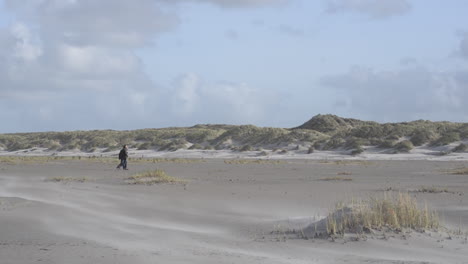 Two-men-walking-on-stormy-beach-to-the-dunes