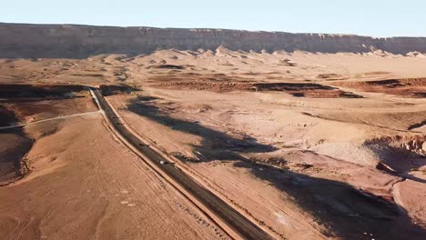 Stunning-Aerial-Cinematic-Shot-of-Cars-Driving-Along-a-Desert-Road