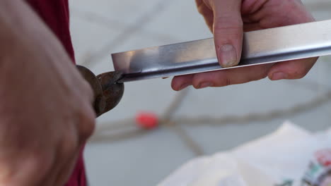 Close-up-of-the-hands-of-a-construction-worker-using-tin-snips-while-cutting-a-piece-of-aluminum-angle-iron-sheet-metal-while-building-a-teardrop-travel-trailer