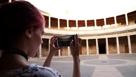 Chica-Pelirroja-Haciendo-Una-Fotografía-Con-Smartphone-A-Un-Monumento-En-Cámara-Lenta,-Granada,-España
