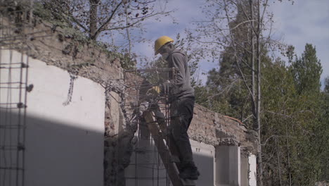 Man-with-a-hammer-drill-eliminating-a-portion-of-an-old-wall-in-a-construction-site,-in-Full-Hd-slowmotion-at-60fps