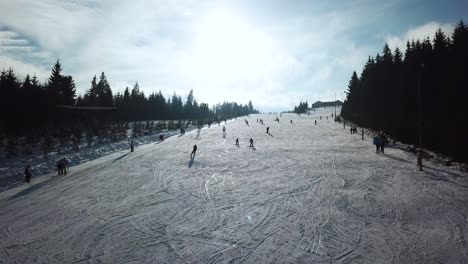 Luftpanorama-Des-Topolita-Schneegipfels-Mit-Menschen,-Die-Den-Hang-Hinunter-Snowboarden-Und-Ski-Fahren,-Während-Die-Drohne-Bergauf-Fliegt