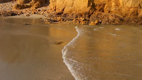 A-close-up-of-the-incoming-tide-rushing-into-the-beach-at-Walkerville-Victoria-Australia-with-the-glow-of-the-sunset