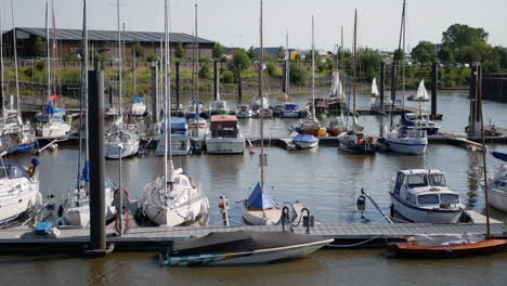 View-from-above-at-little-marina-in-south-of-Hamburg,-Germany-with-sail-boats-and-motor-boats-laying-at-anchor-at-sunny-day