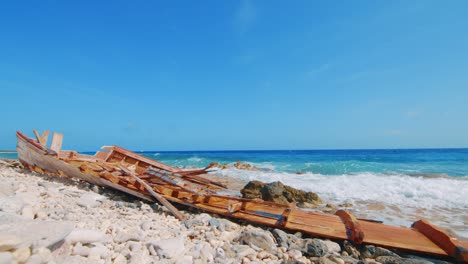Zerstörtes-Hölzernes-Fischerboot-Am-Felsigen-Strand-In-Curacao