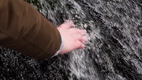 Nahaufnahme-Einer-Weiblichen-Hand,-Die-In-Zeitlupe-Eiskaltes-Wasser-Aus-Dem-Wasserfall-Berührt