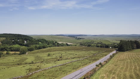 Aerial-Zoom-of-a-paved-road-through-a-rural-landscape-with-rolling-hills-in-Dartmoor,-England