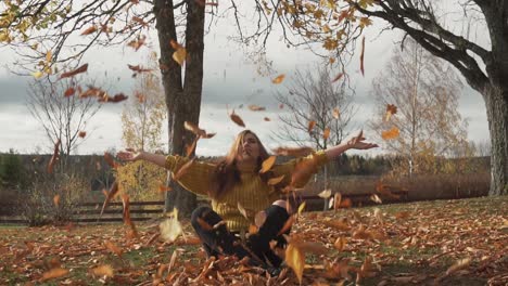 Adult-girl-is-throwing-leaves-sitting-under-the-trees-with-Autumn-colours