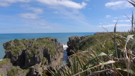 Reveal-shot-of-the-famous-pancake-rocks,-waves-hit-the-cliffs-in-the-background,-Punakaiki,-New-Zealand