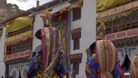 Monjes-Con-Máscaras-Coloridas-Y-Vestidos-Parados-En-El-Viento-Frente-A-Los-Turistas-En-El-Festival-Hemis-En-El-Monasterio